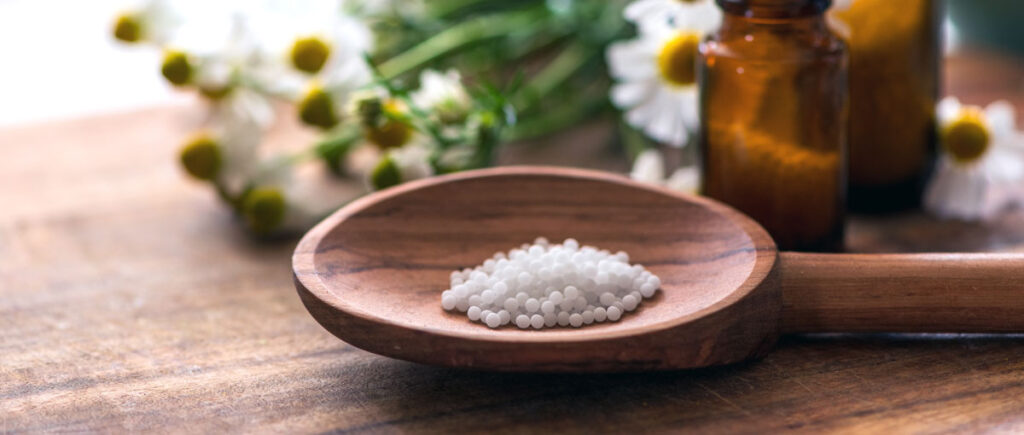 Homöopathische Globuli Kügelchen auf einem Holzlöffel.